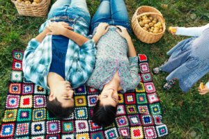 33126844-Loving-couple-resting-on-a-crocheted-blanket-on-the-grass-in--Stock-Photo
